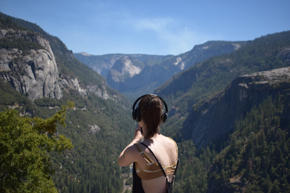 Una mujer con auriculares parada en la cima de una montaña