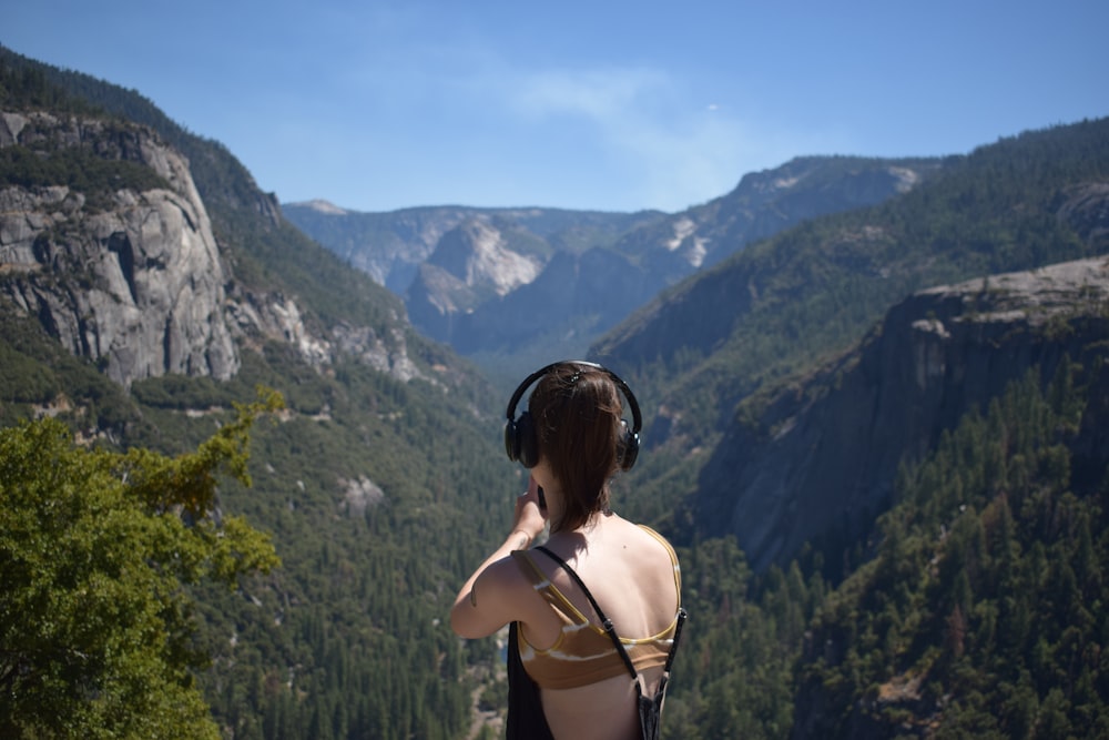a woman wearing headphones standing on top of a mountain