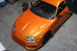A bright orange car parked in a clean, elegant garage after a full interior and exterior detail.