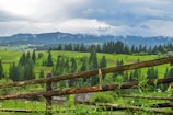 a wooden fence in front of a lush green hillside