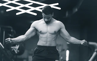 a shirtless man in a gym holding a barbell