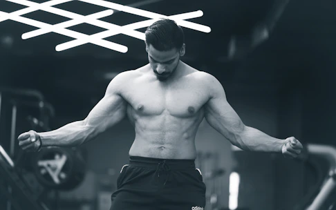 a shirtless man in a gym holding a barbell