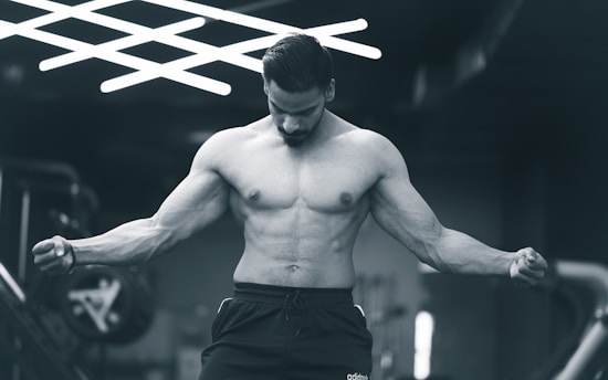 a shirtless man in a gym holding a barbell