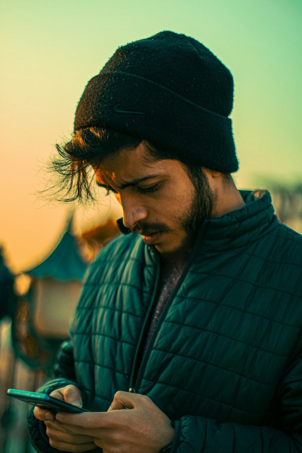 a man wearing a beanie looking at his cell phone