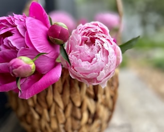 a basket filled with pink flowers sitting on top of a wooden table