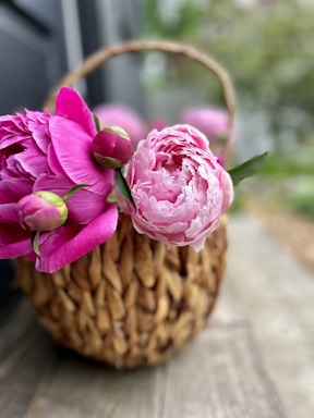 a basket filled with pink flowers sitting on top of a wooden table