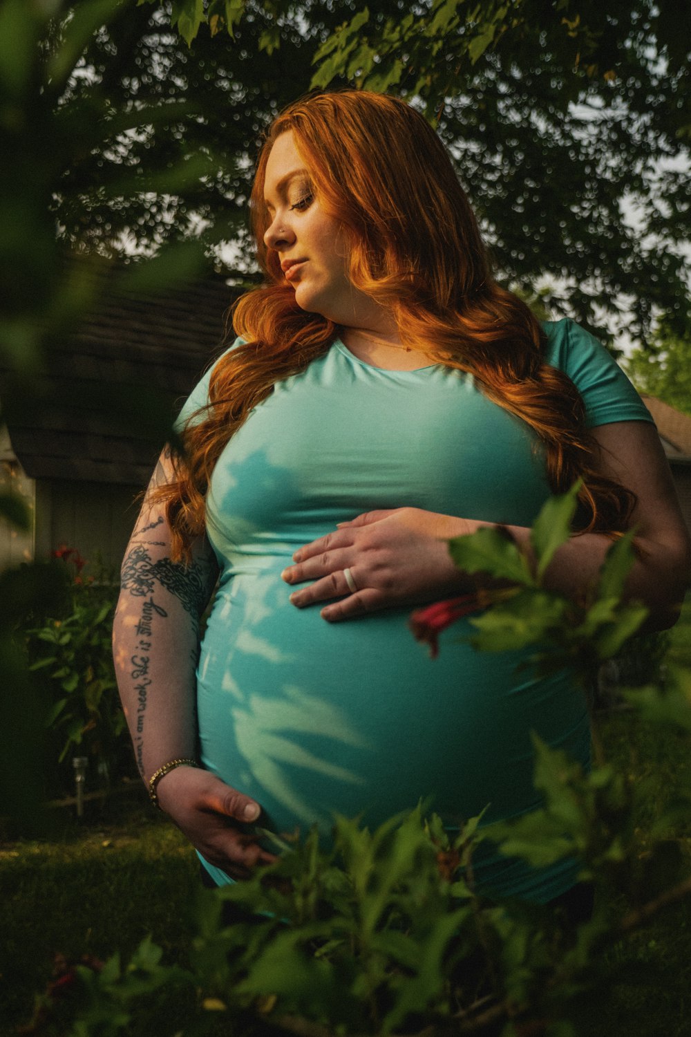 a pregnant woman in a blue dress standing in a garden