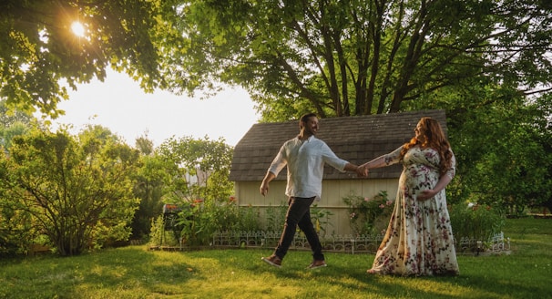 A serene moment of the couple holding hands and walking through a garden adorned with fairy lights at dusk.