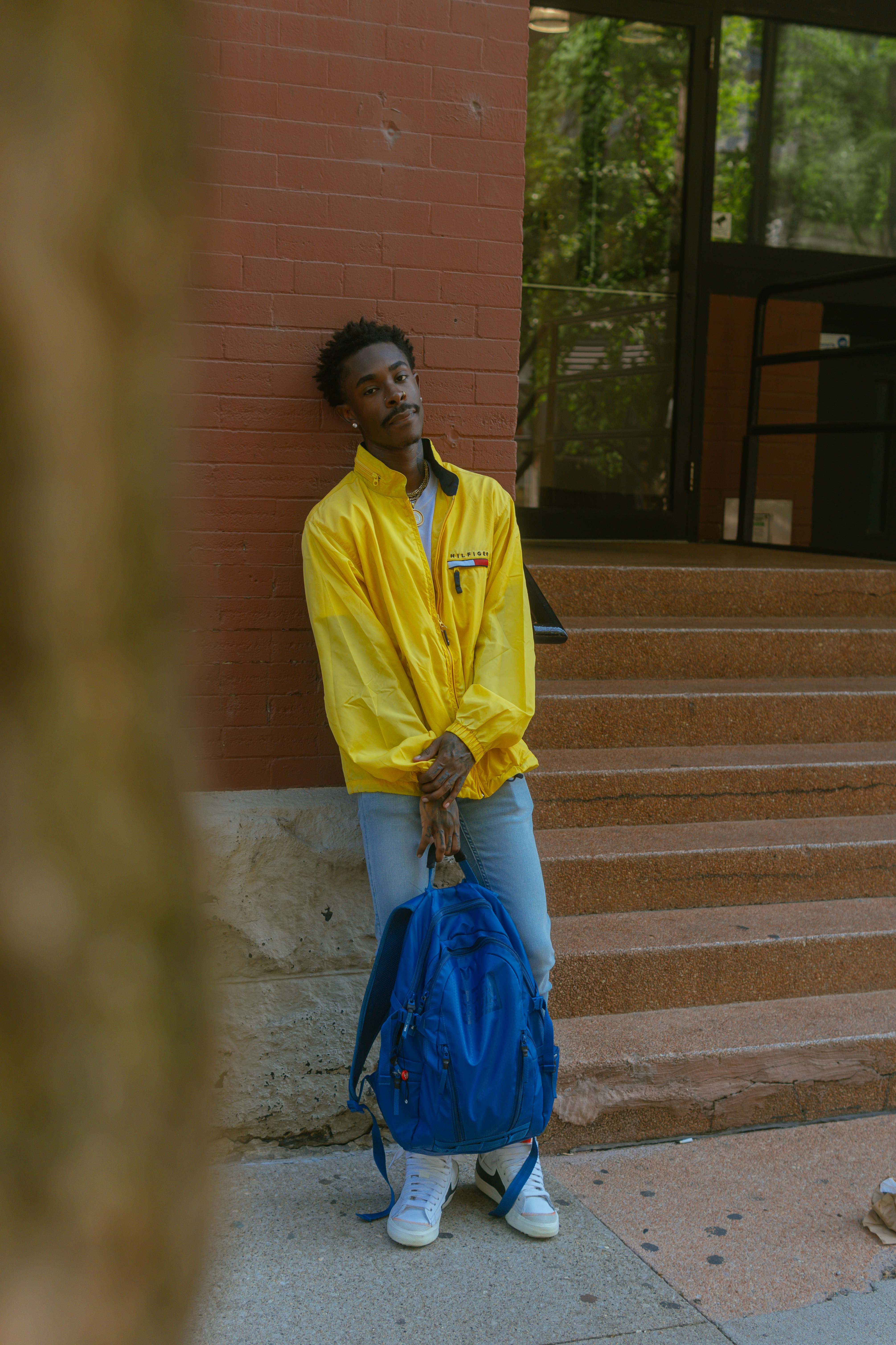 a man in a yellow rain coat is holding a blue bag