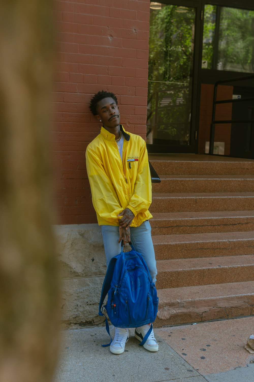 a man in a yellow rain coat is holding a blue bag