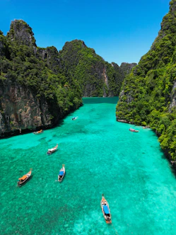 Longtail boats on the turquoise water of Pileh Lagoon surrounded by limestone cliffs