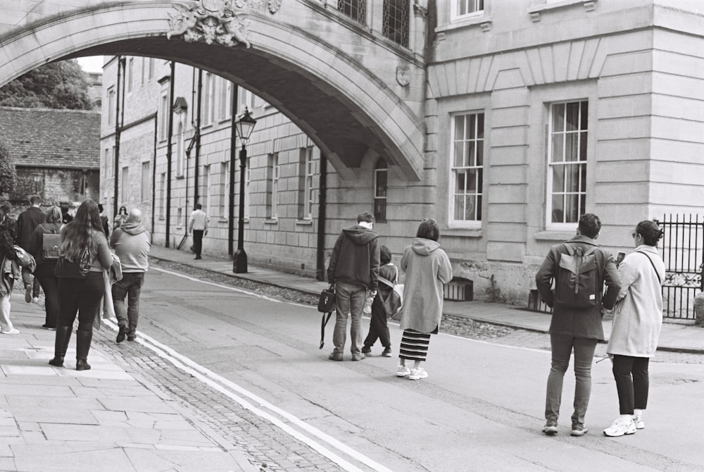 a group of people walking down a street next to a bridge