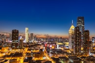 A bustling cityscape at dusk, illuminated with royal blue and silver lights, capturing vibrant urban energy.