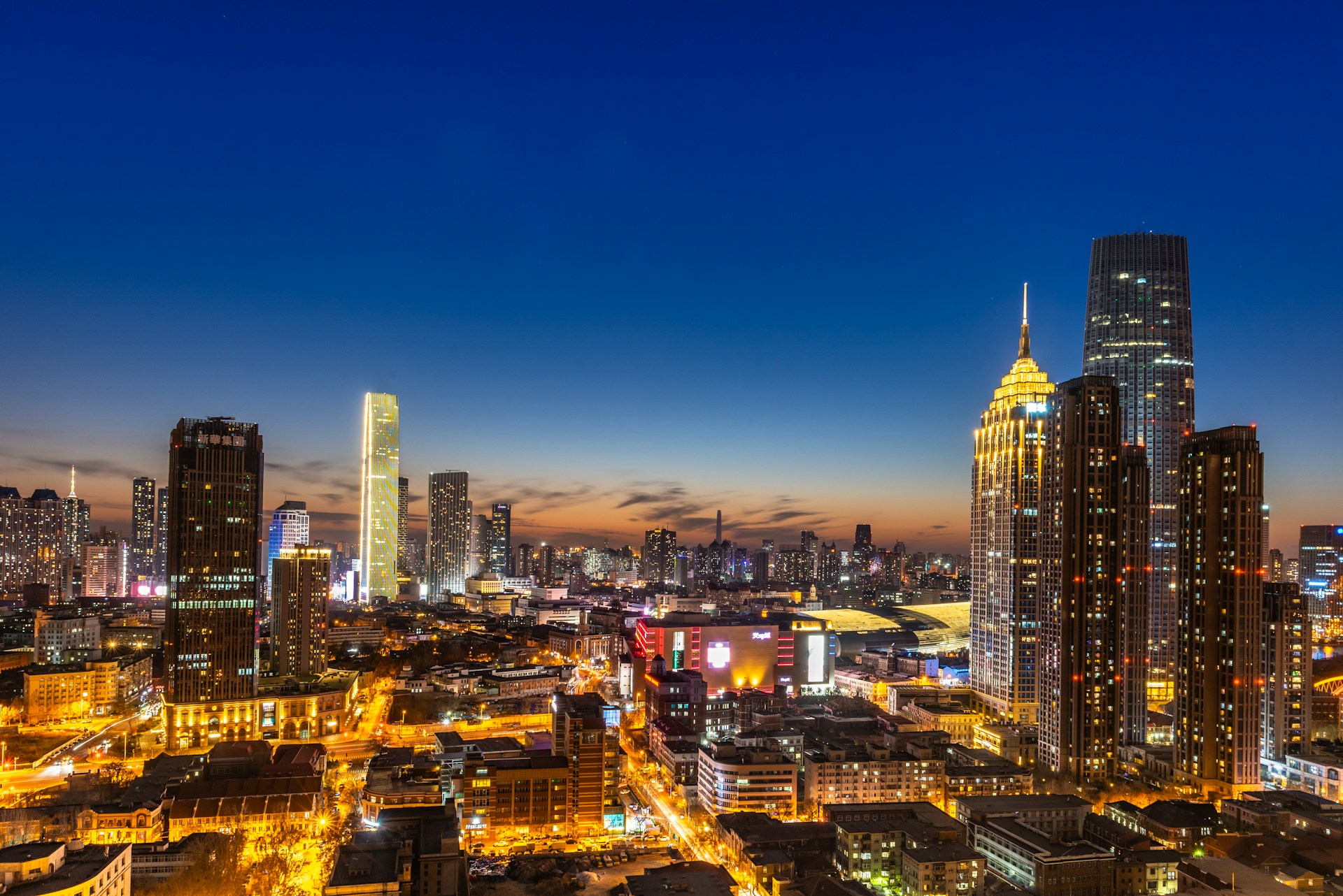 A vibrant cityscape at dusk, capturing the glowing lights and bustling streets that tell a story of urban life.