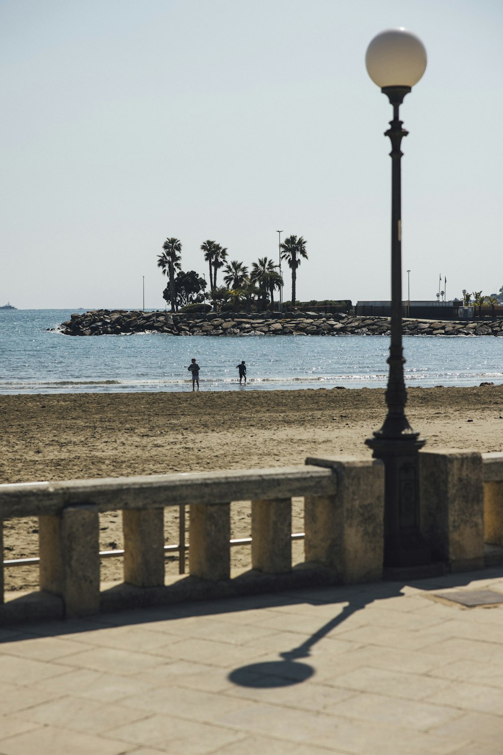 a street light sitting on the side of a beach