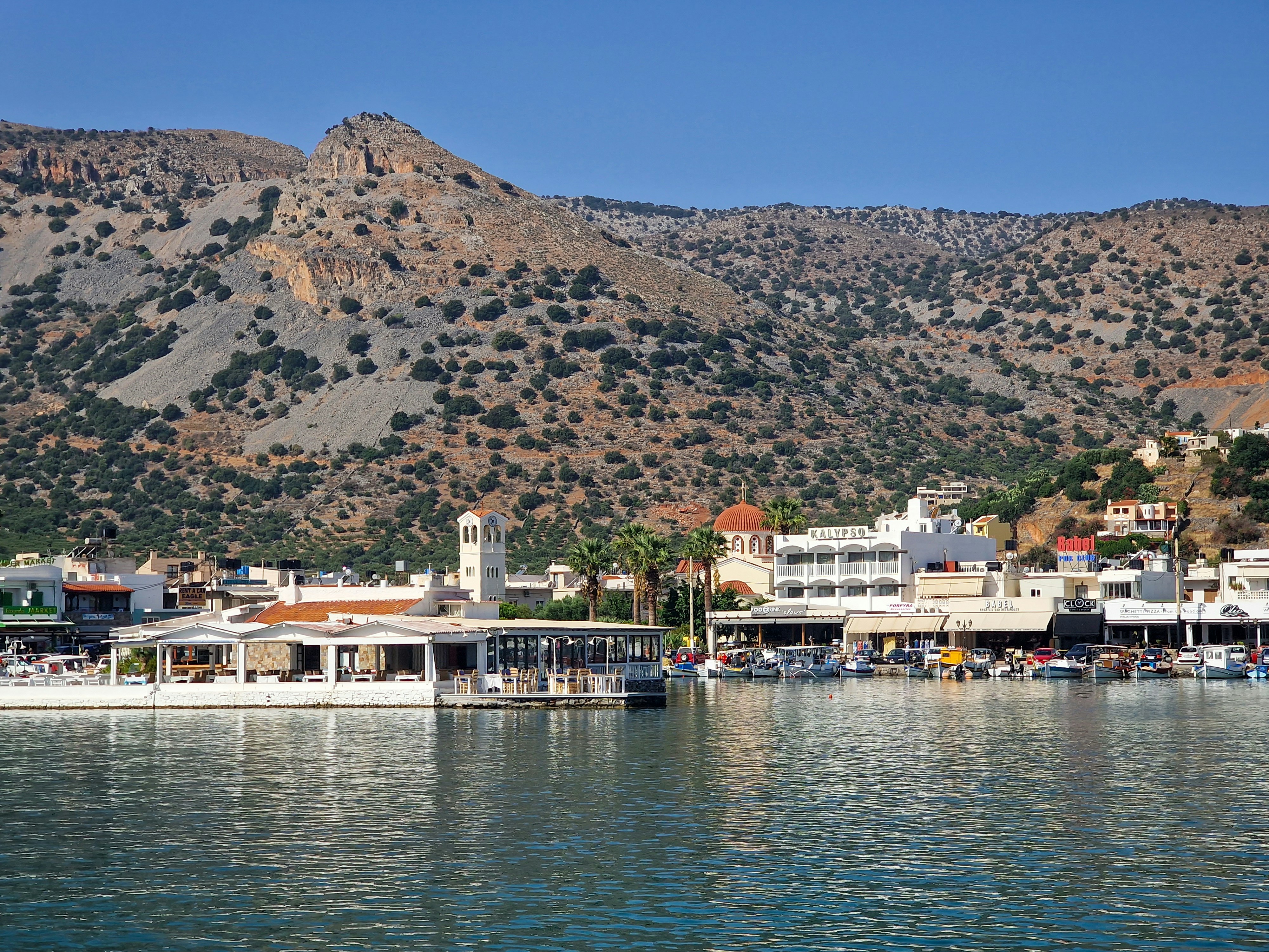 a view of a town on the water with mountains in the background, 
