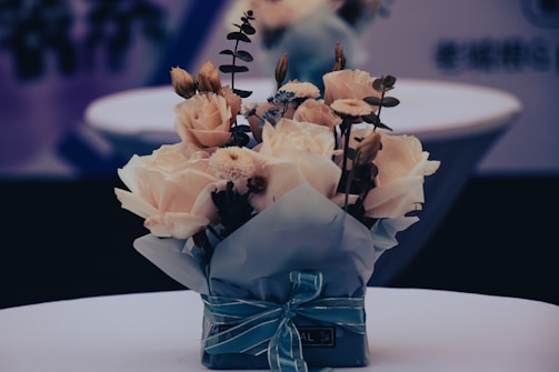 Finished bouquet wrapped in cream paper tied with a soft sage ribbon on a wooden table.