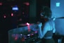 a woman wearing headphones standing in front of a dj's turntable