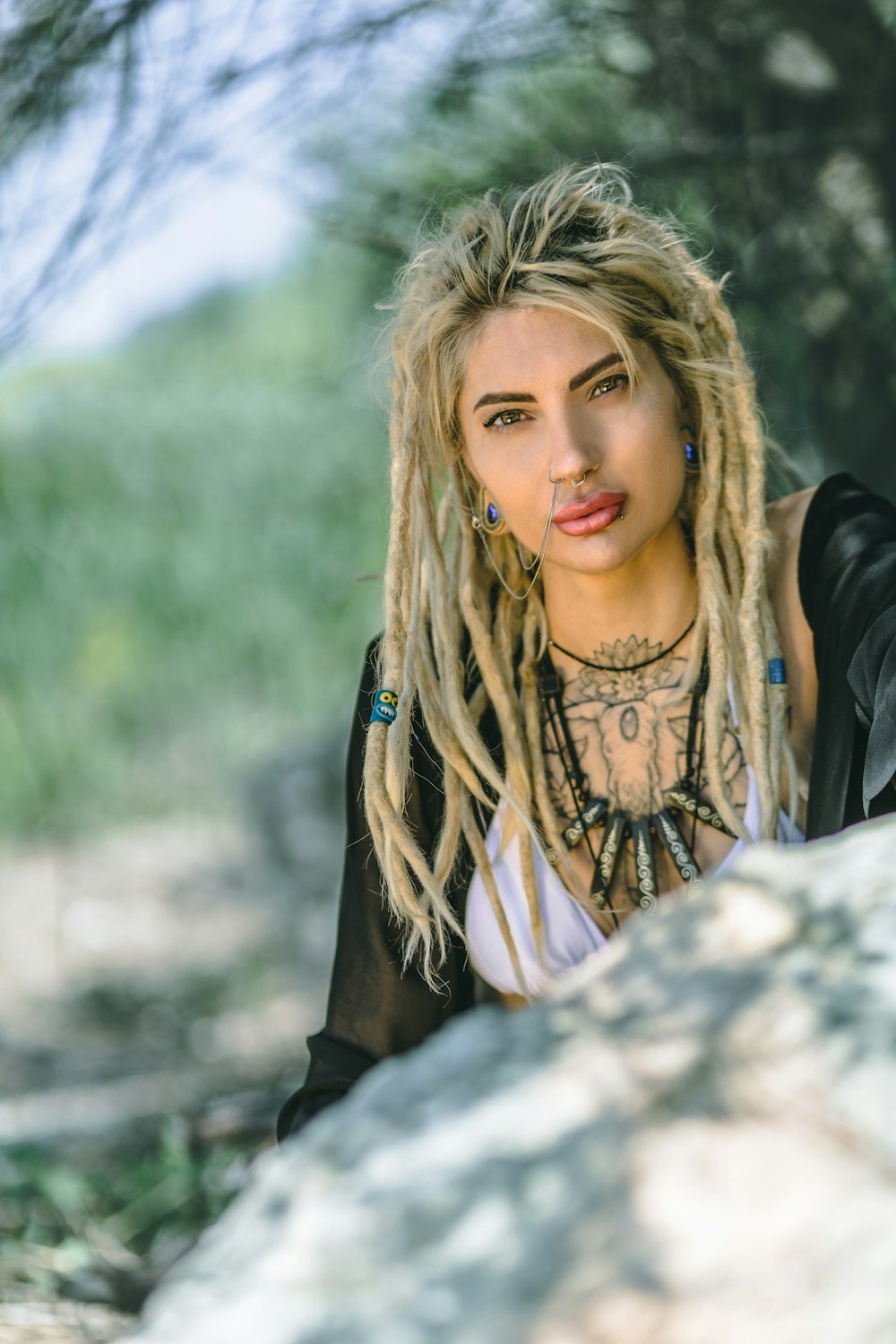 a woman with dreadlocks standing next to a rock