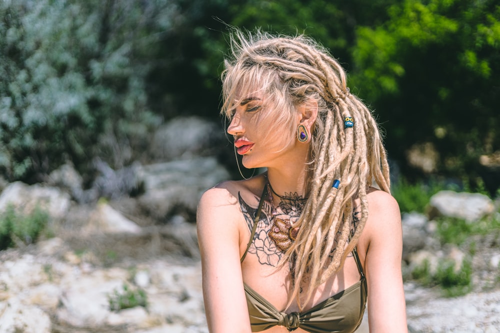 a woman with dreadlocks sitting on a rock