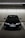 A black Honda car is parked in an indoor parking garage, lined with parking spaces and illuminated by overhead fluorescent lights. The concrete walls and ceiling create an industrial atmosphere.