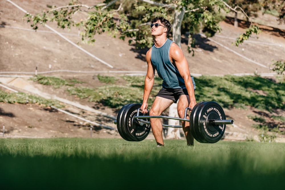 a man lifting a barbell in a park