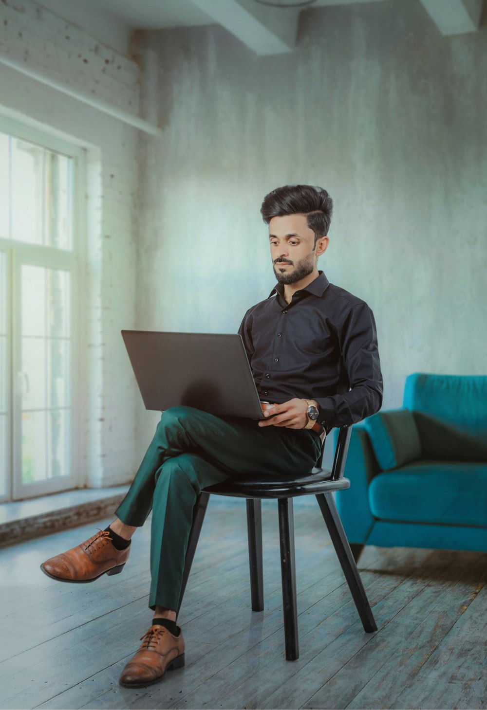 a man sitting on a chair using a laptop