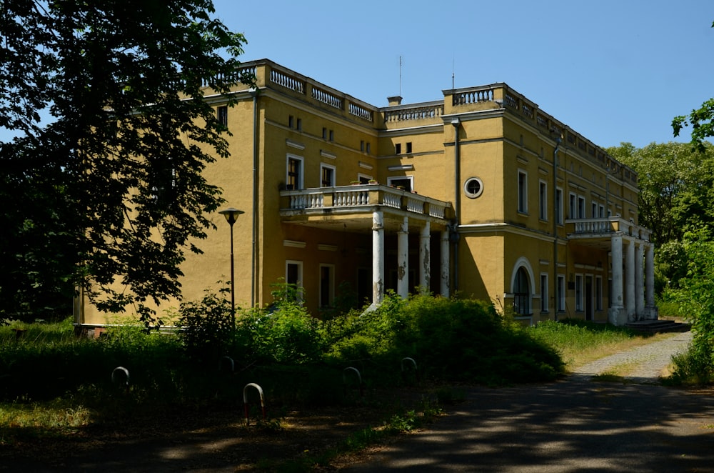 a large yellow building sitting next to a lush green forest