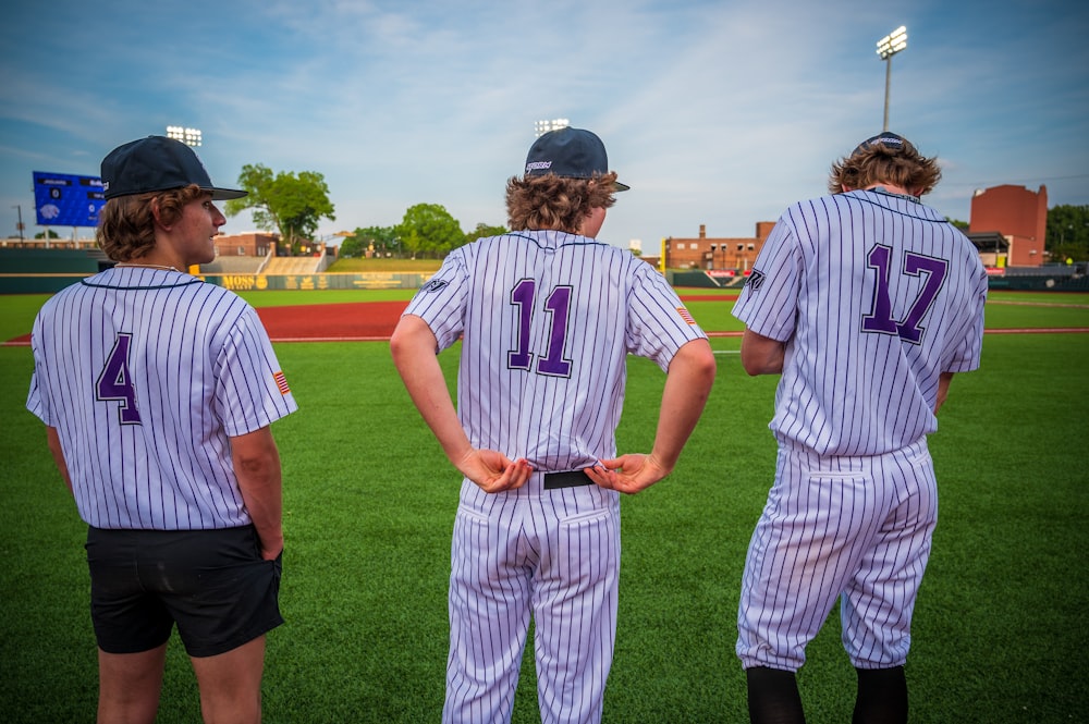 three young baseball players standing on a baseball field