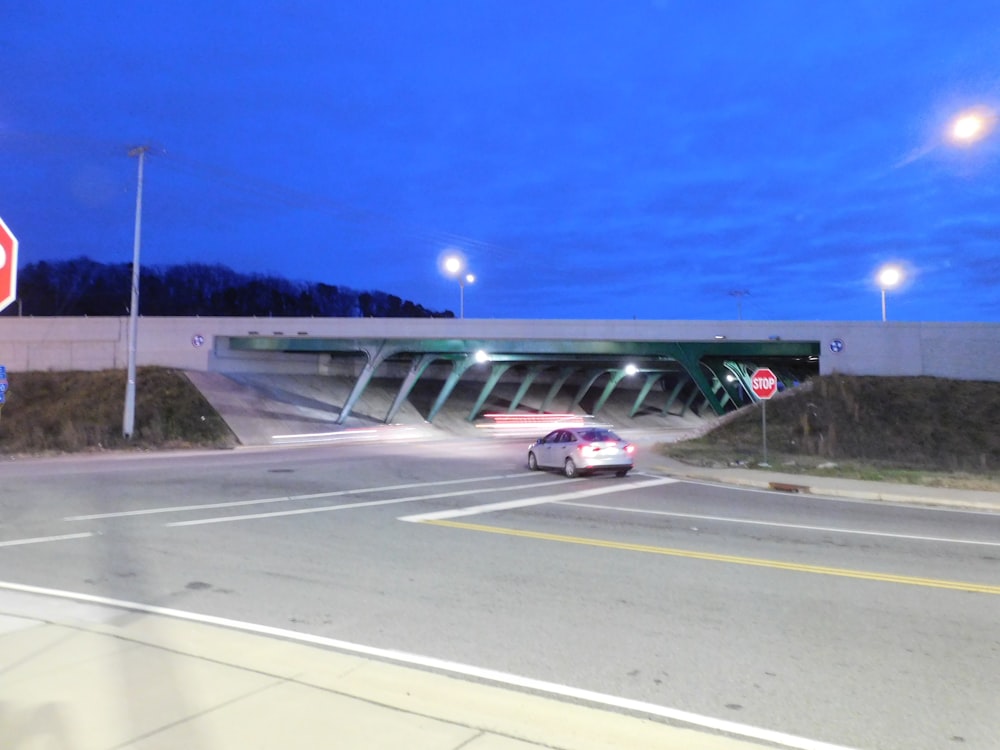 a stop sign at an intersection with a bridge in the background