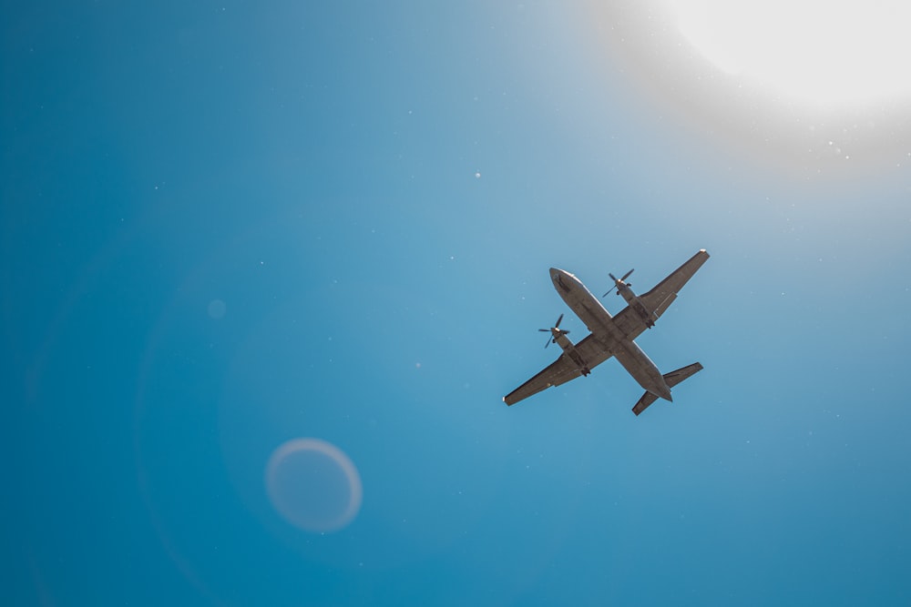 a plane flying in the sky with the sun in the background