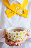 a person holding a bowl with daisies in it