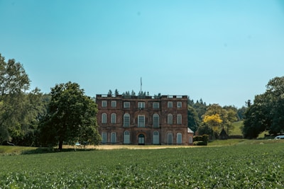 a large brick building sitting in the middle of a lush green field