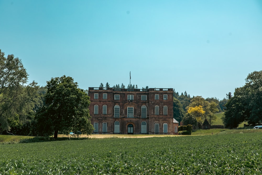 a large brick building sitting in the middle of a lush green field