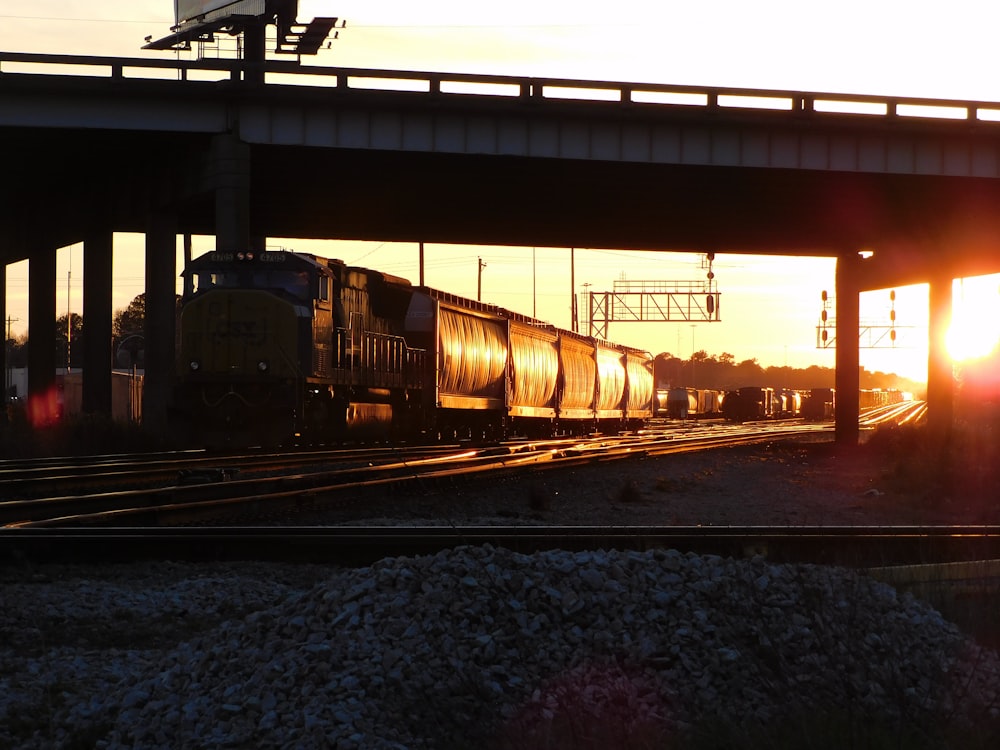 a train traveling down train tracks under a bridge