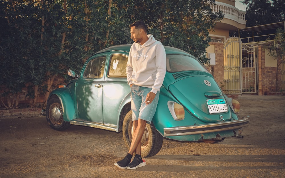 a man standing next to a blue vw bug