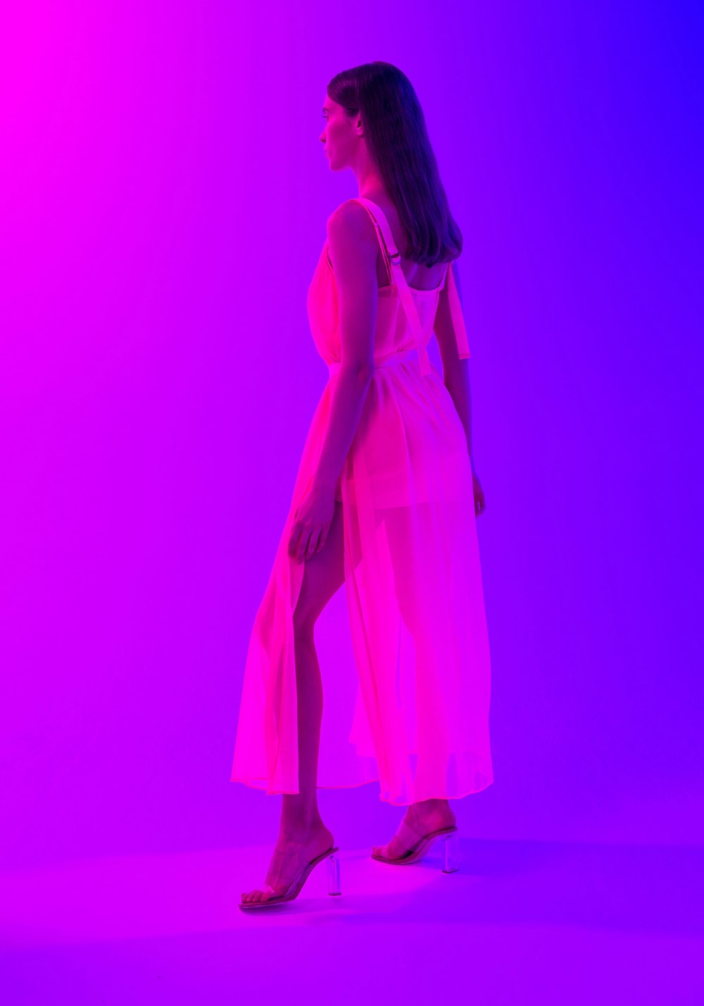 a woman in a white dress standing in front of a purple background