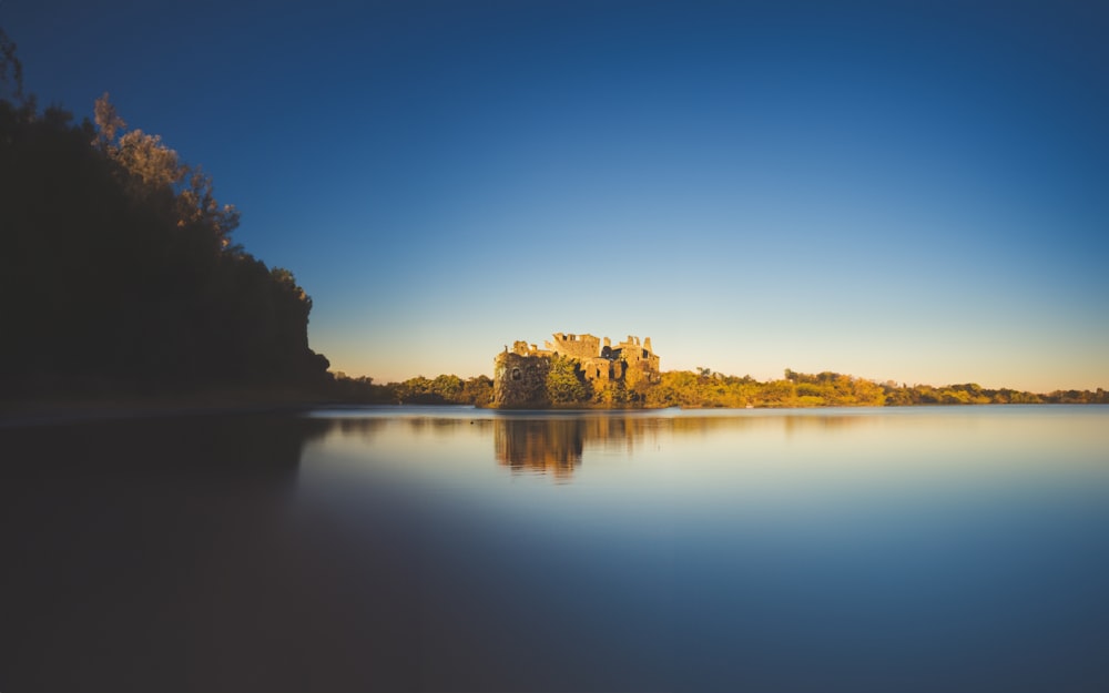 a castle sitting on top of a lake next to a forest