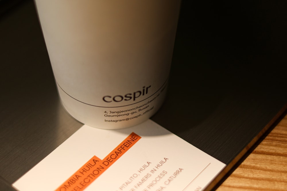 a coffee cup sitting on top of a table next to a business card