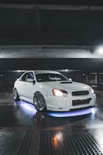 A sleek car with custom rims and tinted windows parked in a modern garage.