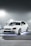 A vibrant car with custom-painted brake calipers and underglow lights illuminating the ground beneath it.