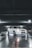 A white sports car with customized features is parked inside a dimly lit garage. The car is illuminated by underglow lights, creating a striking effect against the reflective, wet surface of the floor. Overhead lighting casts subtle shadows and highlights the sleek design of the vehicle.