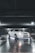 A white sports car with customized features is parked inside a dimly lit garage. The car is illuminated by underglow lights, creating a striking effect against the reflective, wet surface of the floor. Overhead lighting casts subtle shadows and highlights the sleek design of the vehicle.