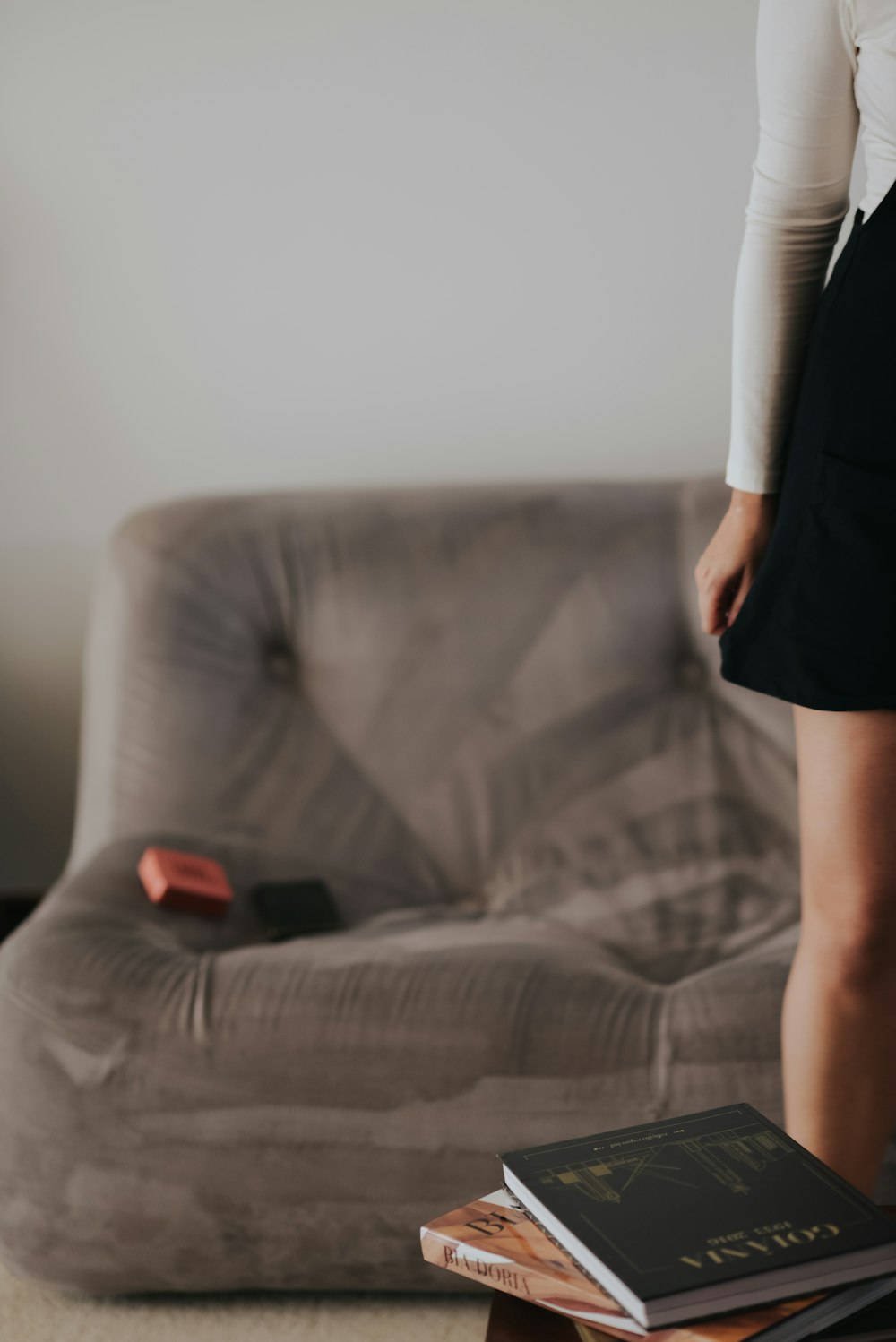 a woman standing on a couch next to a stack of books