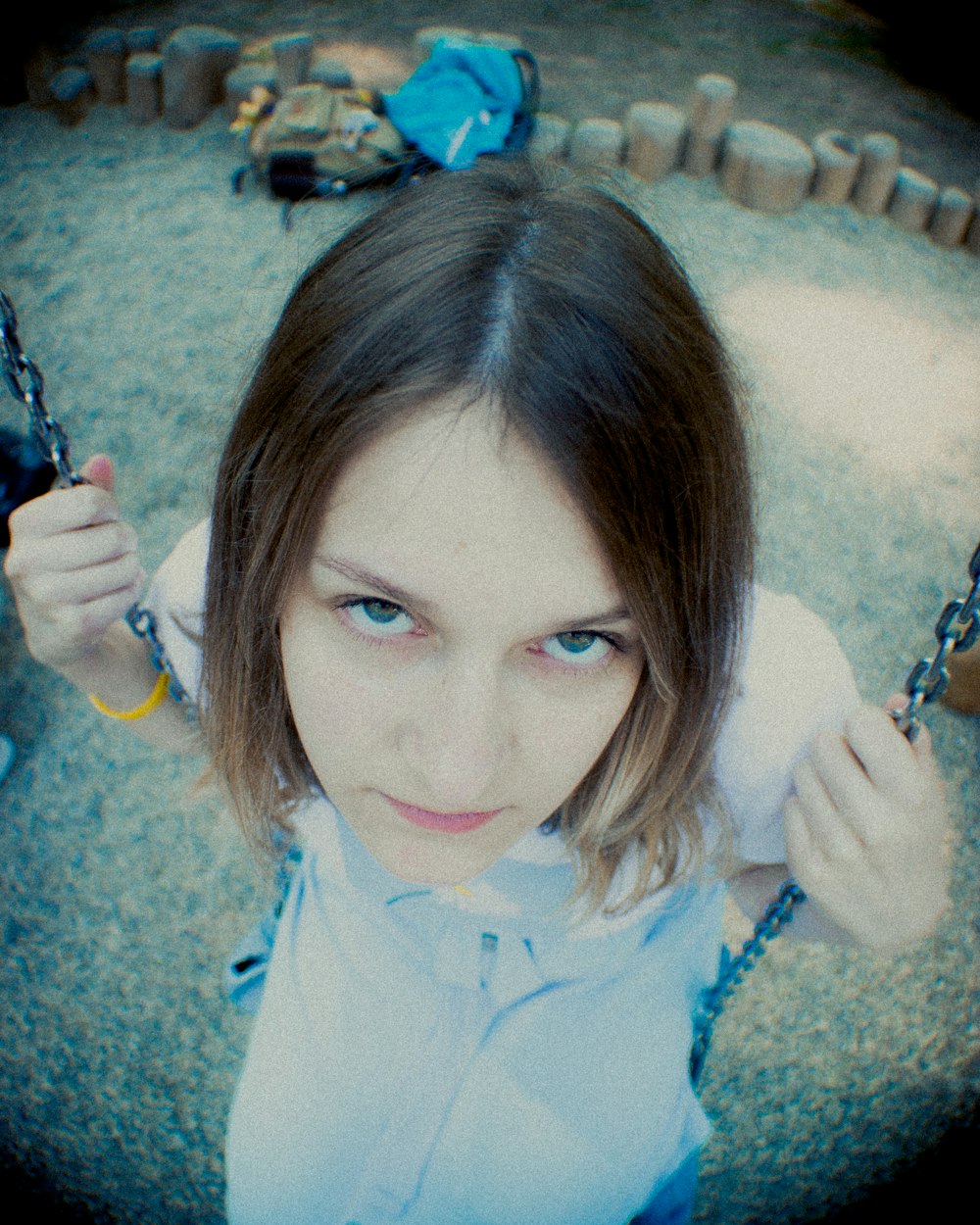 a young girl sitting on a swing with a bottle in her hand