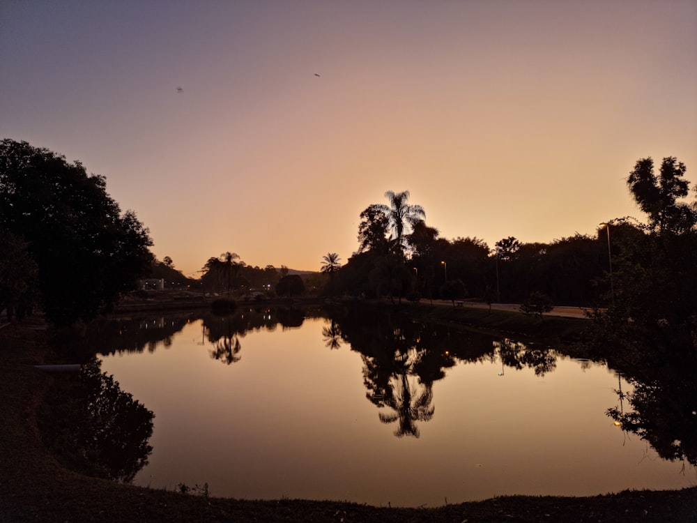 the sun is setting over a small lake