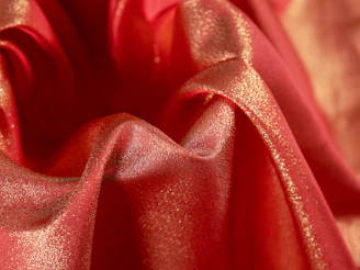 Artistic shot of flowing red satin fabric intertwined with sparkling diamond-like highlights on a dark background