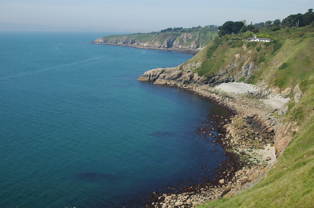 a large body of water sitting next to a lush green hillside