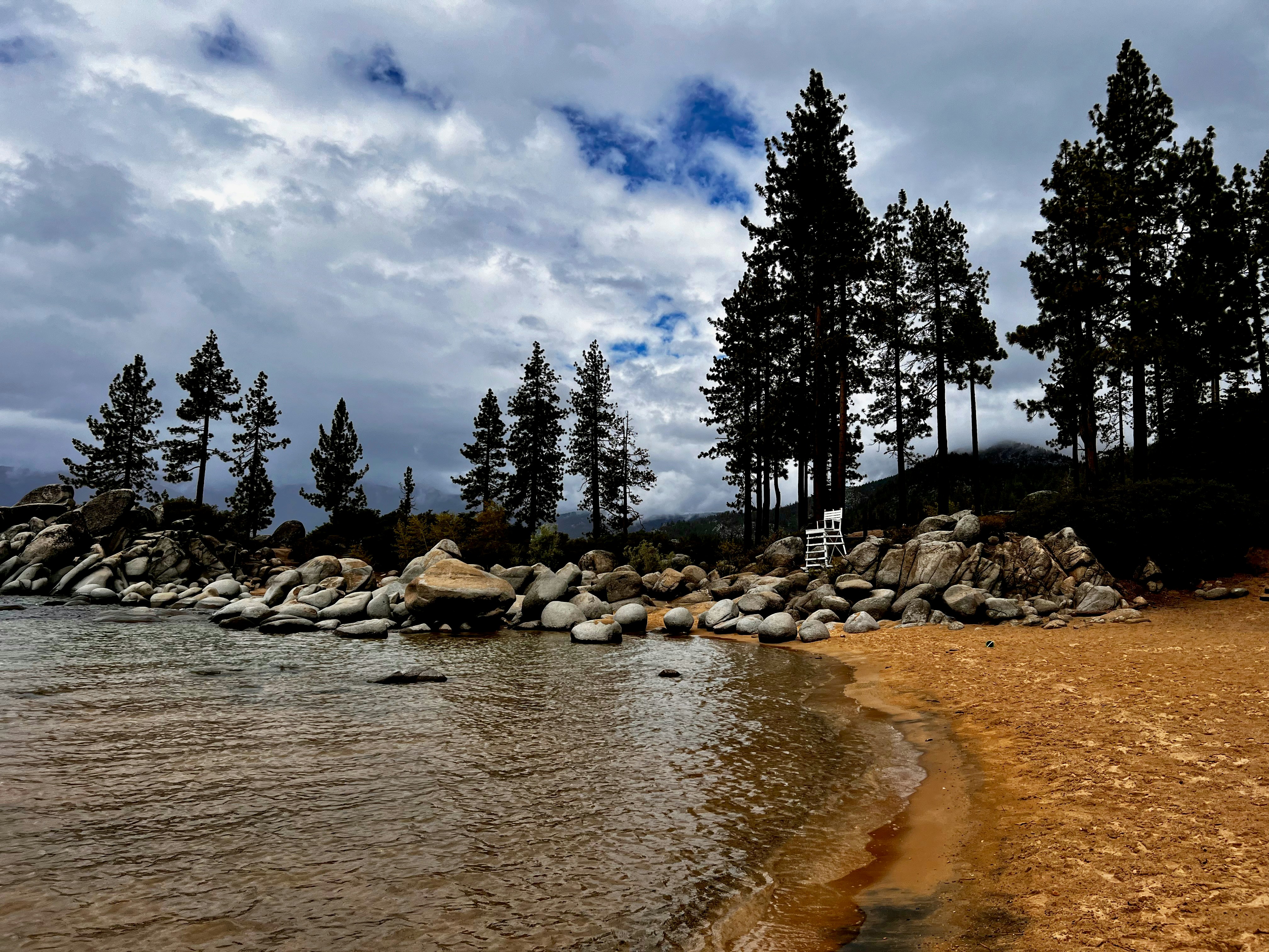 a sandy beach next to a body of water, 