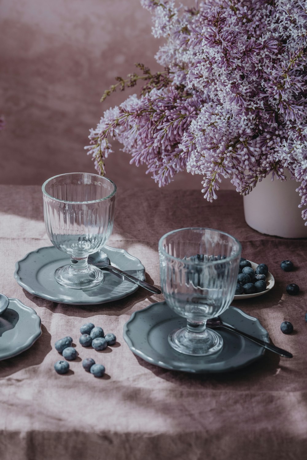 a table topped with plates and cups filled with blueberries